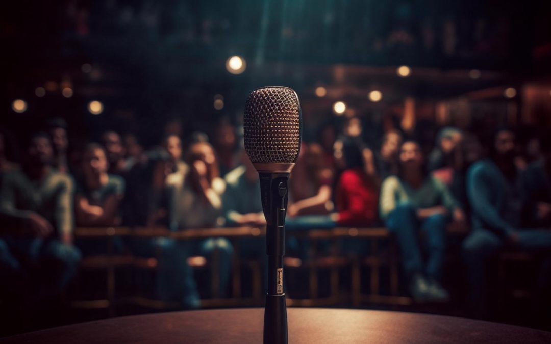 A microphone on stage faces a blurred audience in a dimly lit venue, setting the scene for comedy in corporate events.
