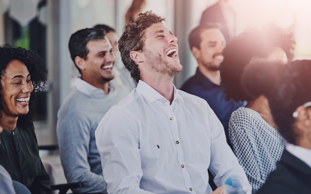 A group of people sitting and laughing together during a lively event or presentation with Jeff Zaret.
