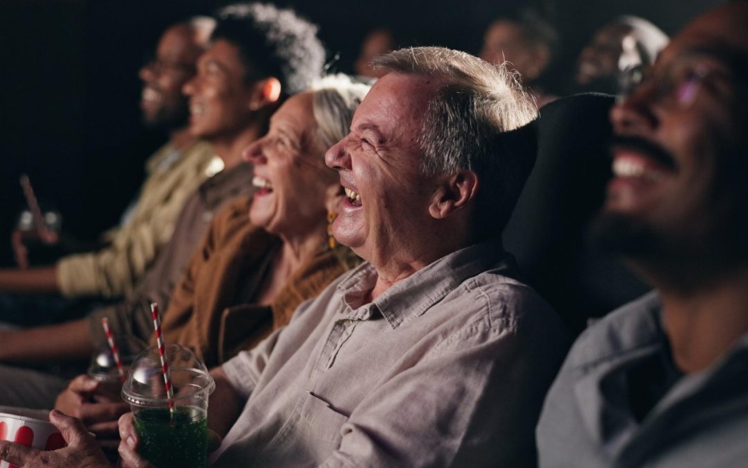 A diverse group of people laughing and enjoying a movie together in a theater.